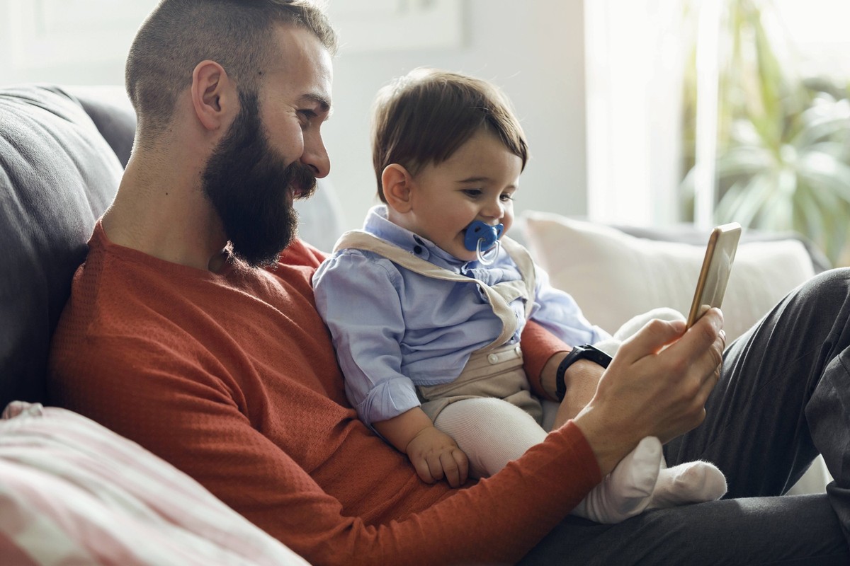 Father with son watching cartoons on smart phone at home model released, Symbolfoto property released, JSRF03102