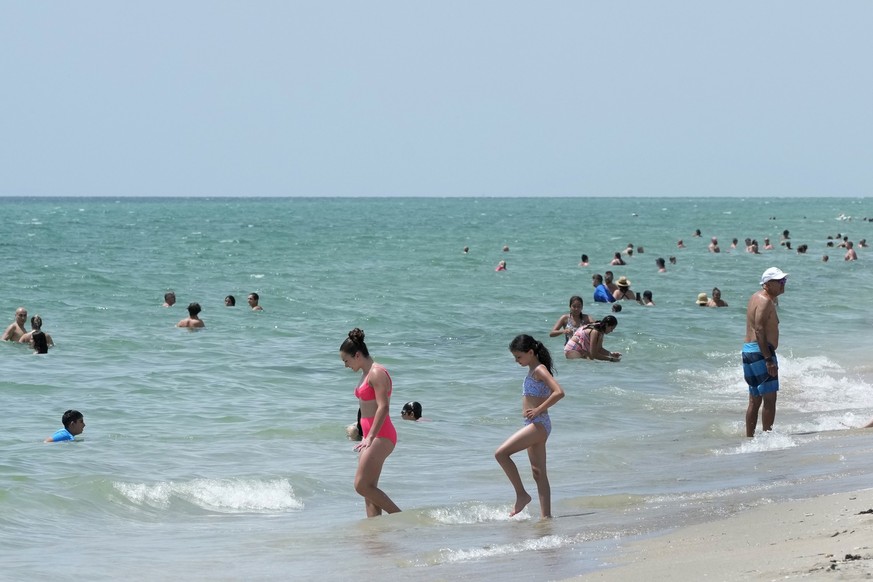 Beach goers take a dip in the Atlantic Ocean at Hollywood Beach, Monday, July 10, 2023, in Hollywood, Fla. Water temperatures in the mid-90s (mid-30s Celsius) are threatening delicate coral reefs, dep ...