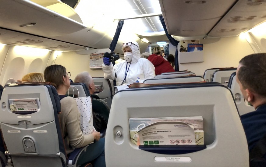 08.03.2020, Russland, Moskau: Ein Arzt in einem Schutzanzug kontrolliert die Temperatur der Passagiere in einem Flugzeug, welches aus Italien am Flughafen Moskau-Scheremetjewo eintrifft. Foto: Alexand ...