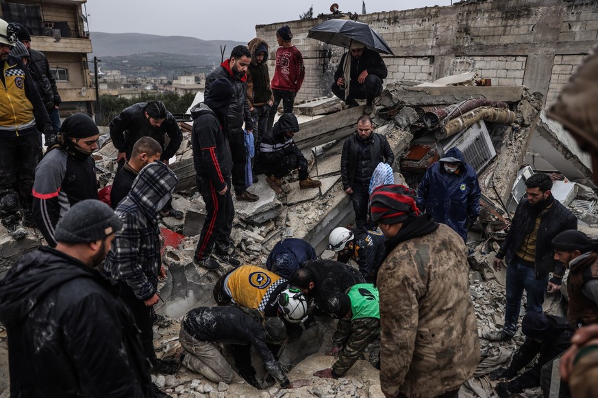06.02.2023, Syrien, Idlib: Syrische Zivilisten und Mitglieder der Weißhelme arbeiten an der Rettung von Menschen, die nach einem Erdbeben der Stärke 7,8 in Syrien unter einem zerstörten Gebäude einges ...