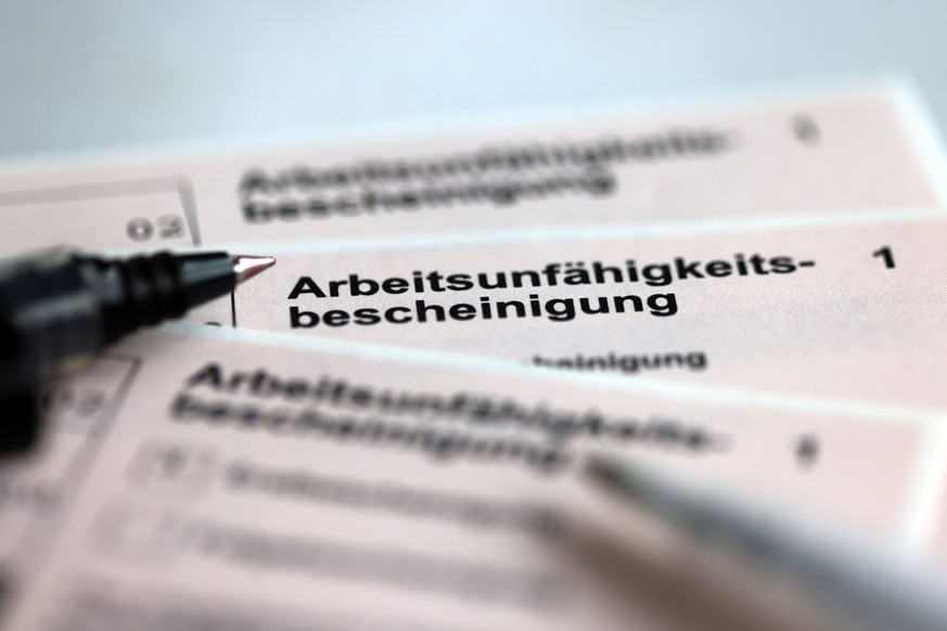 ARCHIV - 14.01.2022, Mecklenburg-Vorpommern, Schwerin: Stifte liegen auf den Arbeitsunfähigkeitsbescheinigungen für Arbeitnehmer im Falle einer Krankschreibung durch den Arzt. (Zu dpa «Barmer: Risikof ...