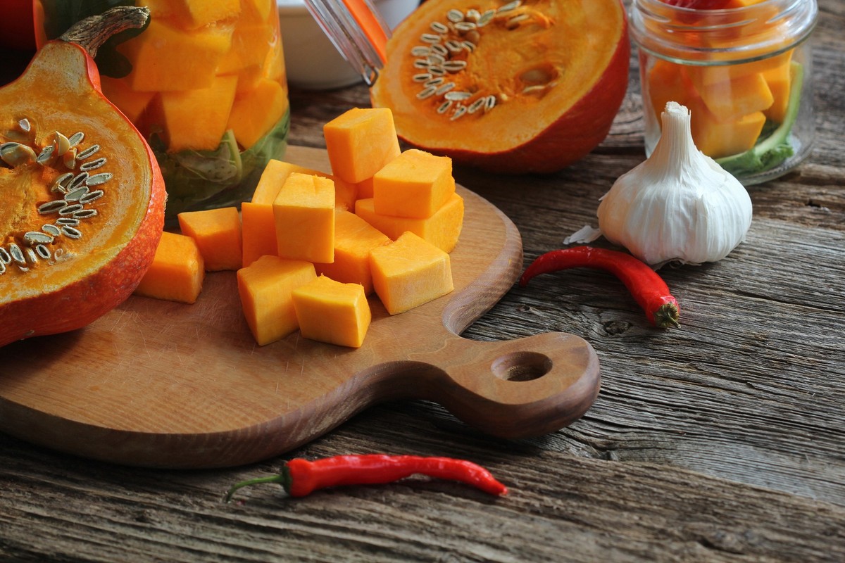 Chopped pumpkin on rustic cutting board and ingredients for tasty vegetarian cooking, dark styled, Chopped pumpkin on rustic cutting board and ingredients for tasty vegetarian cooking, dark styled .,  ...