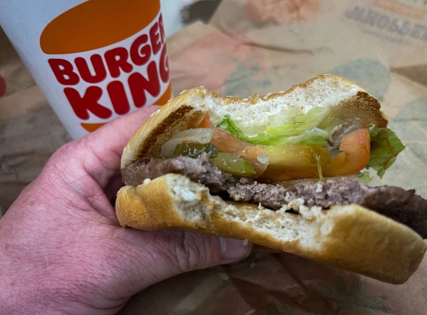 FLEET, UNITED KINGDOM - MARCH 19: In this photo illustration, a man eats a Whopper Meal at branch of the fast food restaurant Burger King, on March 19, 2023 in Fleet, England. Founded in 1953 Burger K ...