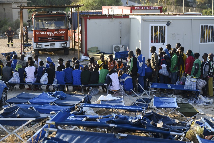 13.09.2023, Italien, Lampedusa: Migranten stehen in einem Aufnahmezentrum für Migranten. Der Stadtrat der italienischen Mittelmeerinsel Lampedusa hat angesichts Tausender neu angekommener Bootsmigrant ...