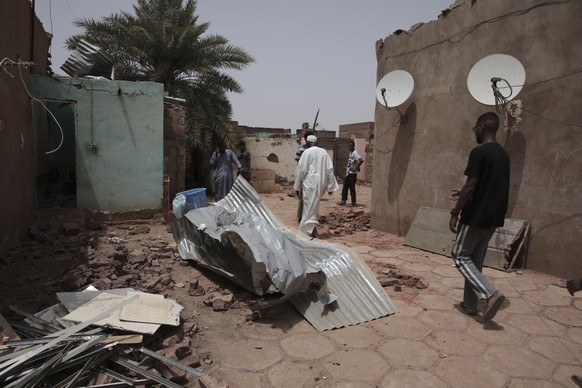 25.04.2023, Sudan, Khartum: Menschen gehen an einem Haus vorbei, das bei den jüngsten Kämpfen beschädigt wurde. Im Sudan sind vor mehr als einer Woche schwere Kämpfe zwischen dem Militär und Paramilit ...
