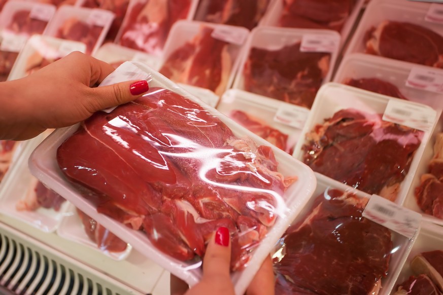 Image of packaged meat with woman hand in the supermarket