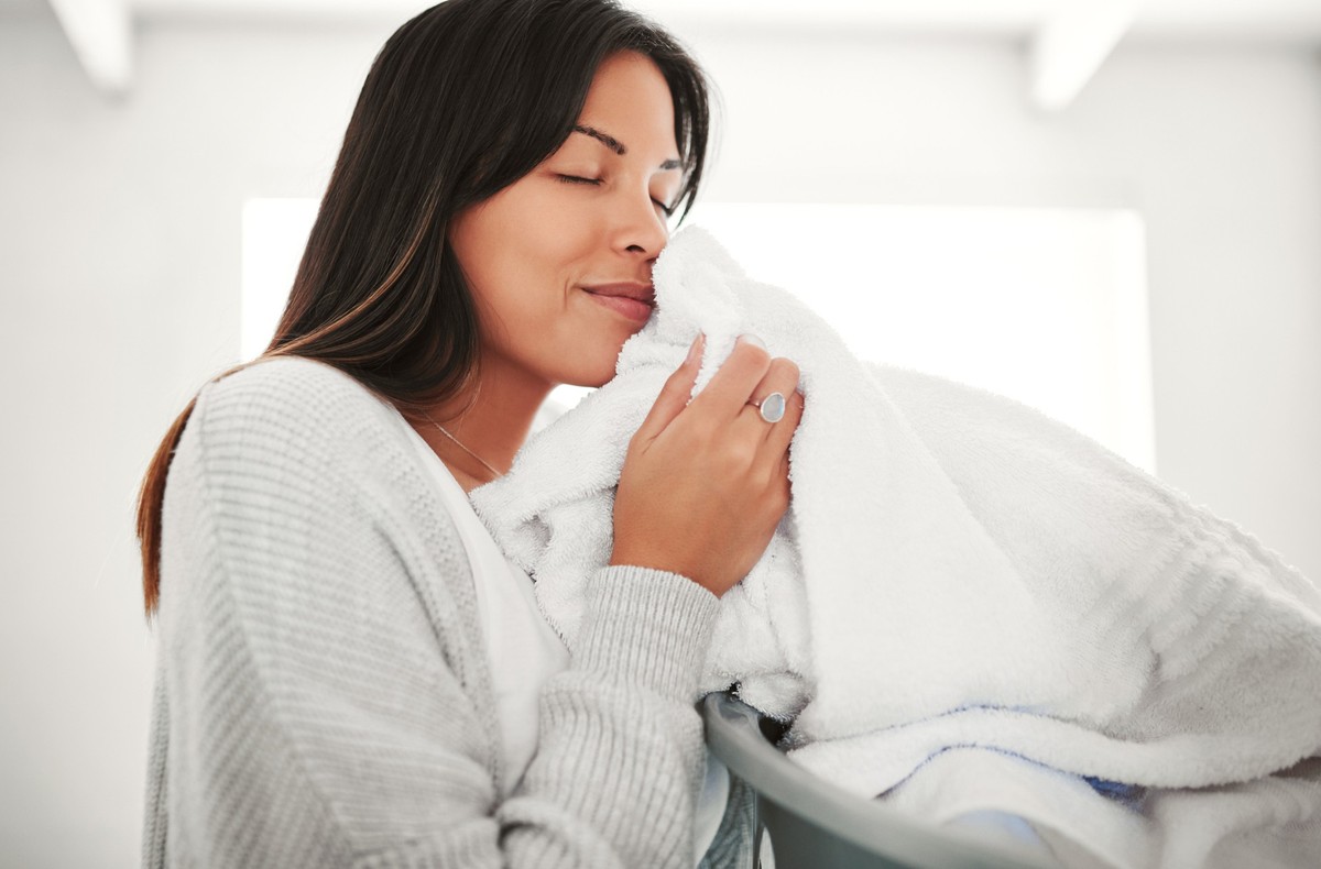 Cropped shot of an attractive young woman smelling clean laundry at home