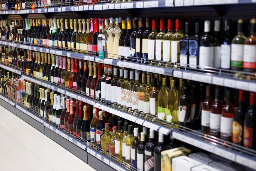 Shelves with variety of alcohol for sale in the supermarket. Vodka, wine, champagne and other alcohol.