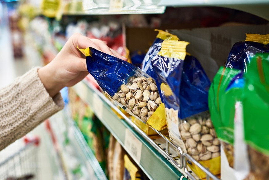 Buyer hand with the packing of salted pistachios in the store