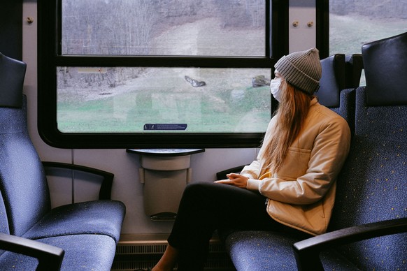 Junge Frau mit Maske im Zug
