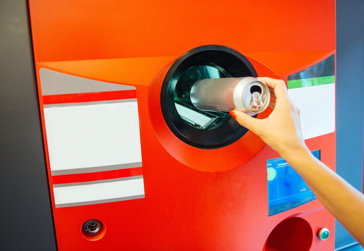 Recycling machine and woman throwing empty beer can in it. Location: Berlin, Germany, Europe