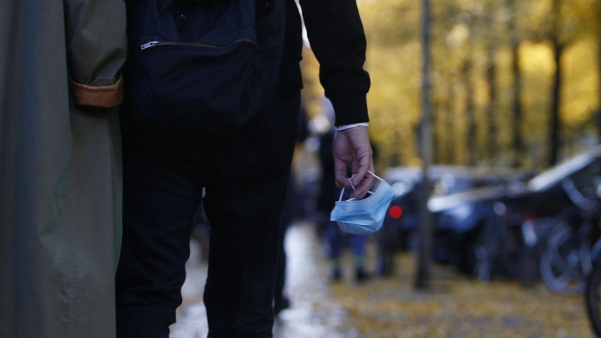 BERLIN, GERMANY - OCTOBER 24: People carry a protective face masks in the hand as they walk along Bergmanstrasse, one of the main shopping street in Kreuzberg district, on the first day that a require ...