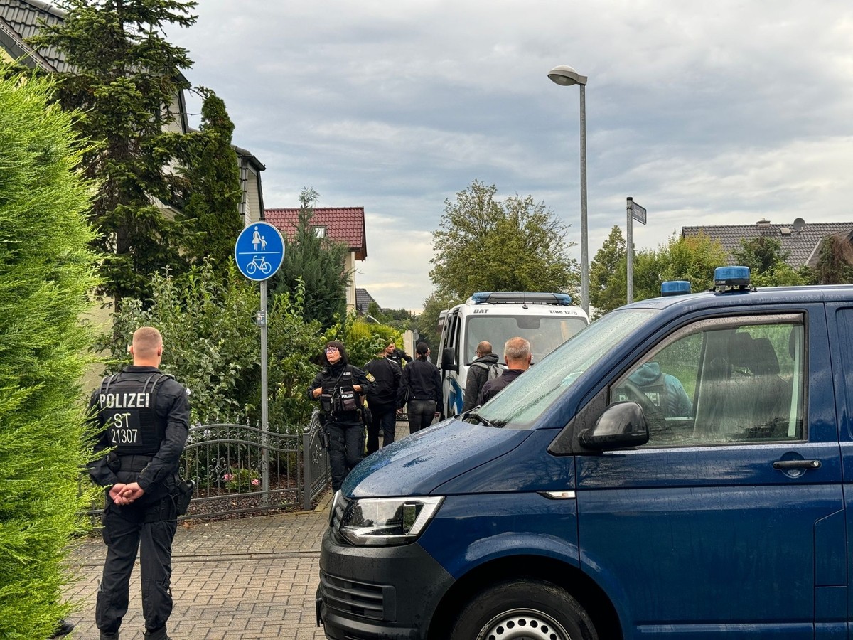 16.07.2024, Sachsen-Anhalt, Magdeburg: Polizisten stehen vor einem Einfamilienhaus auf der Stra�e. Nach Angaben des Bundesinnenministeriums durchsuchen Einsatzkr�fte seit den fr�hen Morgenstunden R�um ...