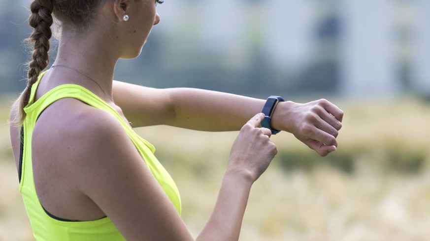 Junge Frau beim Joggen, Dauerlauf, kontrolliert ihre Vitaldaten auf einer Fitness Uhr, Fitness Tracker, Pulsschlag, Herzfrequenz Anzahl der Schritte, Strecke, Zeit, Kalorienverbrauch, *** Young woman  ...