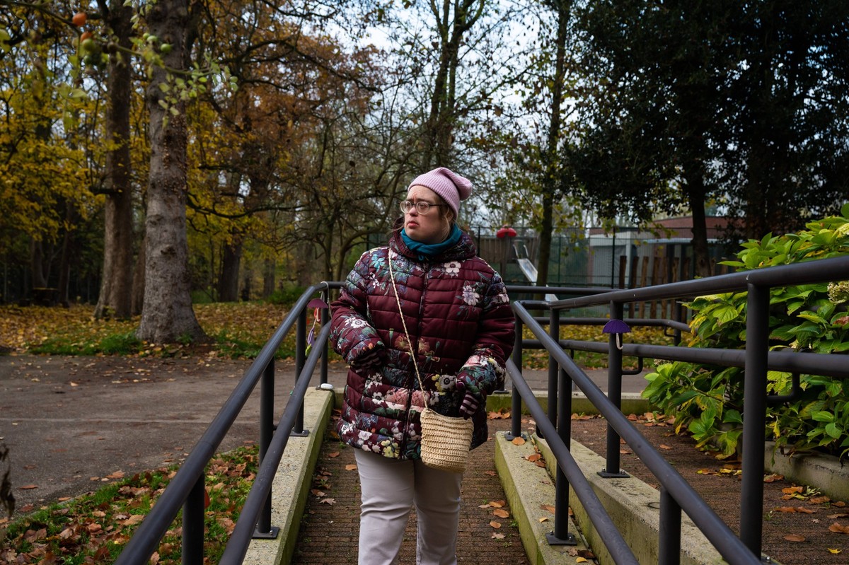40 yo white woman with Down Syndrome, wearing winter clothers walking down and isle outdoors, Flanders, Tienen, belgium