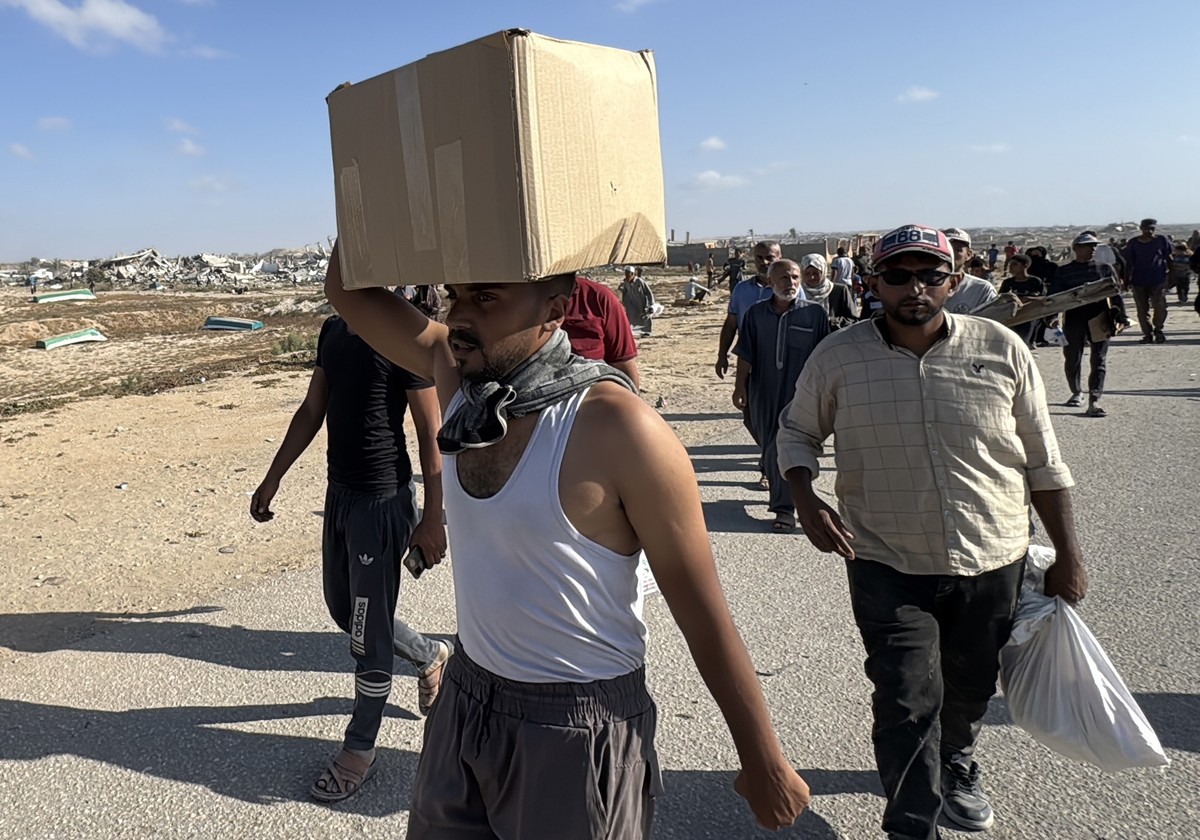 27.05.2025, Pal�stinensische Gebiete, Rafah: Pal�stinenser, die Hilfe suchen, tragen in der N�he einer Hilfsg�terverteilungsstelle der von den USA unterst�tzten Gaza Humanitarian Foundation im s�dlich ...