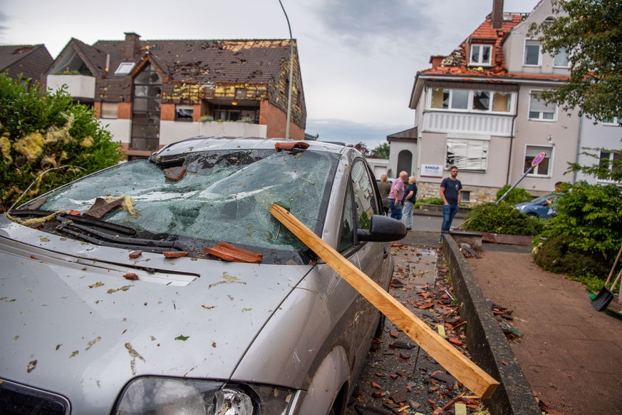 Eine Dachlatte steckt in der Windschutzscheibe eines parkenden Autos.  Ein Unwetter hat in Paderborn große Schäden angerichtet. Dabei wurden nach Polizeiangaben Dutzende Menschen verletzt.