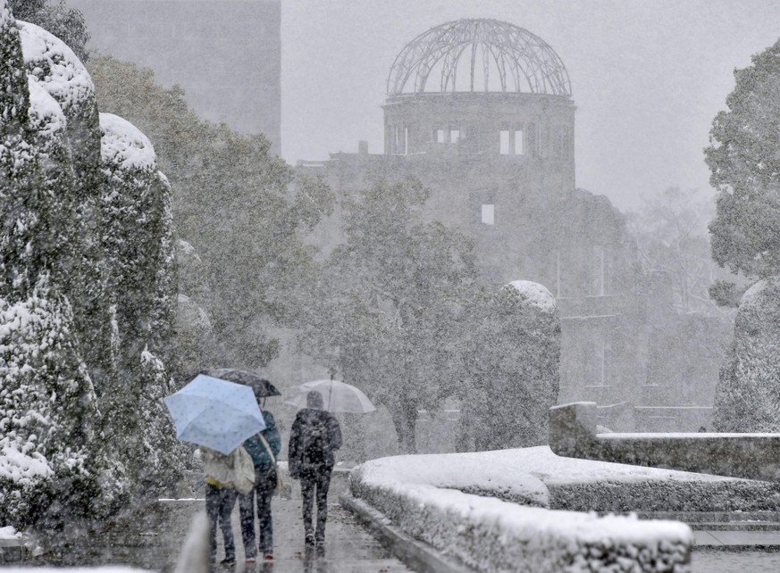 23.12.2022, Japan, Hiroshima: Menschen gehen bei Schneefall durch den Peace Memorial Park in Hiroshima. Das Inselreich Japan erlebt seit Tagen einen schweren Wintereinbruch. Foto: -/kyodo/dpa +++ dpa- ...