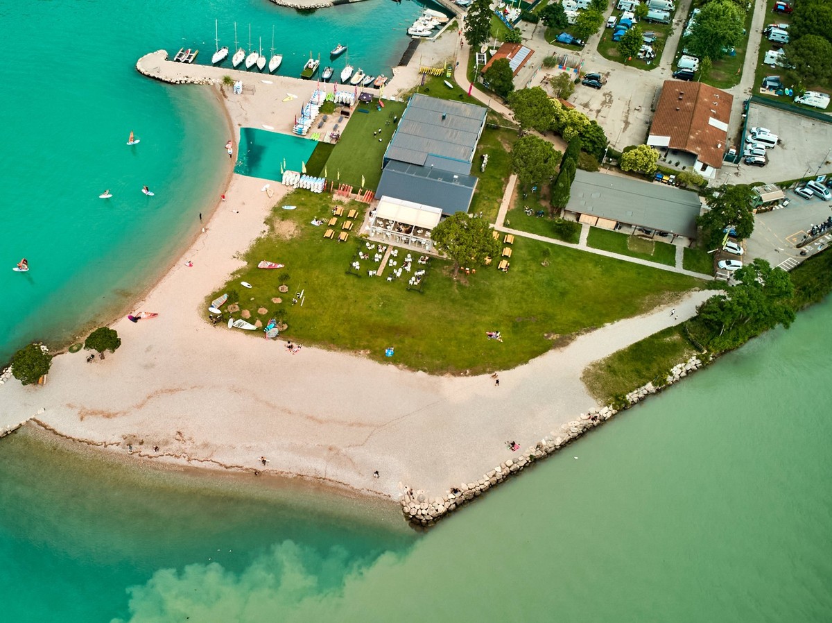 Torbole, Lake Garda, Italy - June 24, 2024: Bathing beach on Lake Garda in the municipality of Torbole , near Riva. Aerial view of surfers on the beach where the river Sarca flows into the lake at Lag ...