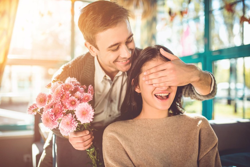 Mann überrascht Frau mit Blumen