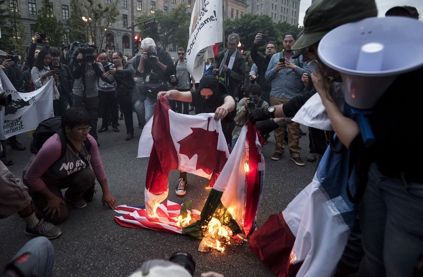 Protesters burn flags of the G7 nations while demonstrating ahead of the G7 Summit in Quebec City on Thursday, June 7, 2018. (Darren Calabrese/The Canadian Press via AP)
