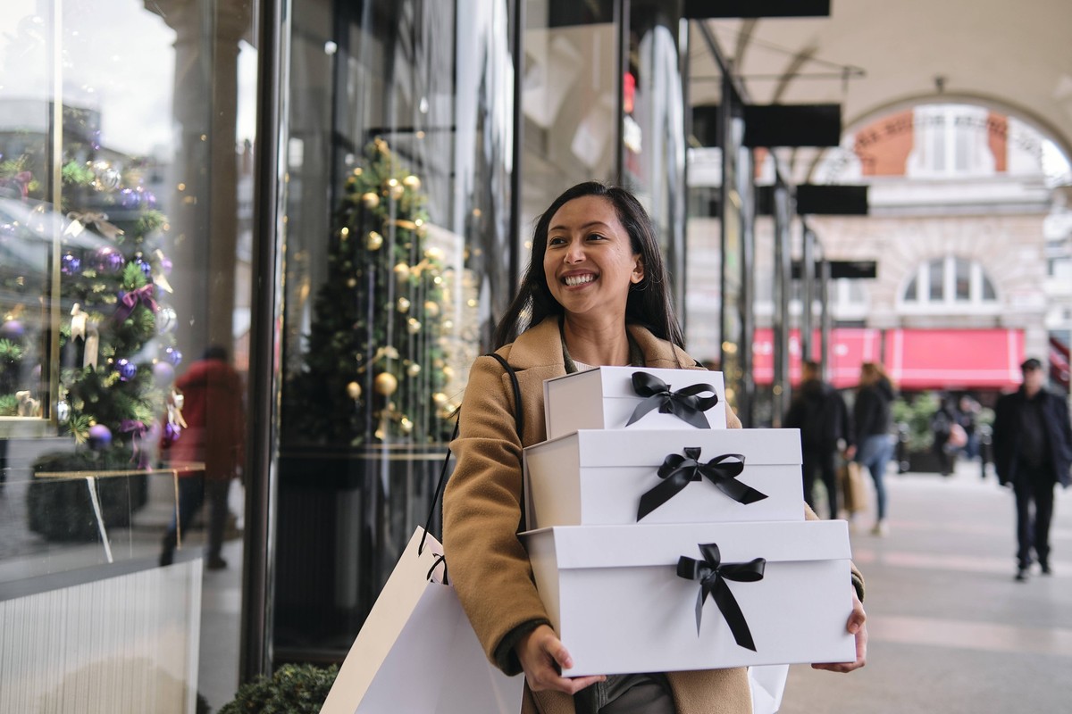 Woman happily carrying gift boxes while shopping during the holiday season outdoors model released, Symbolfoto, ASGF06250