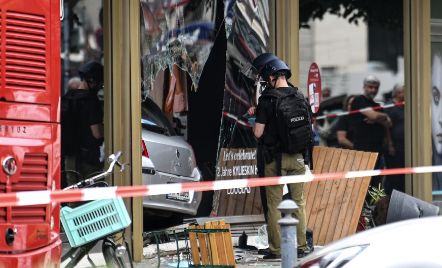 08.06.2022, Berlin: Polizei sichert Spuren an einem zerbrochenen Schaufenster, in dem nach einem Zwischenfall ein Auto steckt. Ein Auto ist in der N