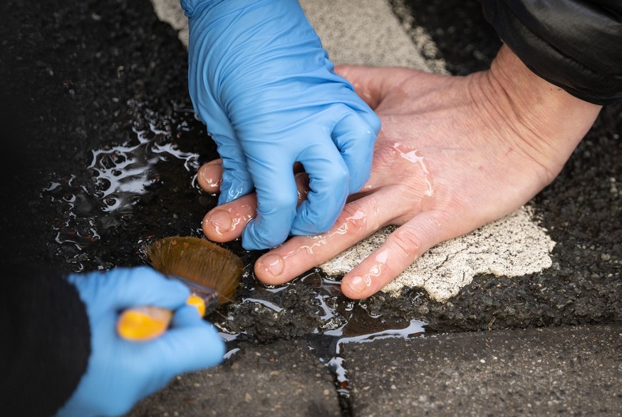 ARCHIV - 22.02.2023, Nordrhein-Westfalen, Dortmund: Ein Klimaaktivist der Gruppe Letzte Generation, der seine Hand auf den Asphalt geklebt hat, um eine Hauptverkehrsstra