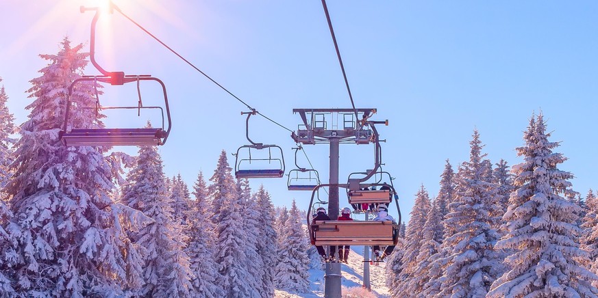 Banner panorama of ski resort, skiers on the ski lift, white snow pine trees at pink sunset or dawn, Kopaonik, Serbia