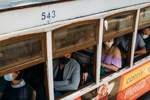 Die zahlreichen Fahrgäste in der Linie 28 der Straßenbahn, die zum Martim Moniz Platz fährt, tragen einen Mund-Nasen-Schutz. In dem beliebten Urlaubsland Portugal steigen die Corona-Zahlen wegen der A ...