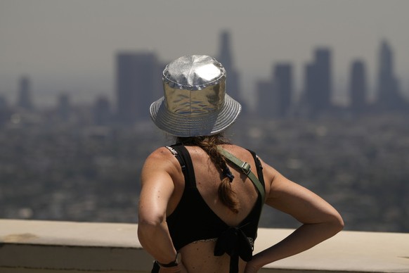 14.07.2023, USA, Los Angeles: Eine Touristin trägt einen silbernen, reflektierenden Hut und blickt vom Griffith Observatory. Für mehr als ein Drittel der Amerikaner gilt die Warnung vor extremer Hitze ...