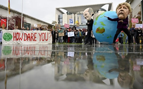 TOPSHOT - Environmentalists hold a banner reading "How dare you", quoting Swedish teenage climate activist Greta Thunberg, and wear masks of German Chancellor Angela Merkel and Finance Minis ...