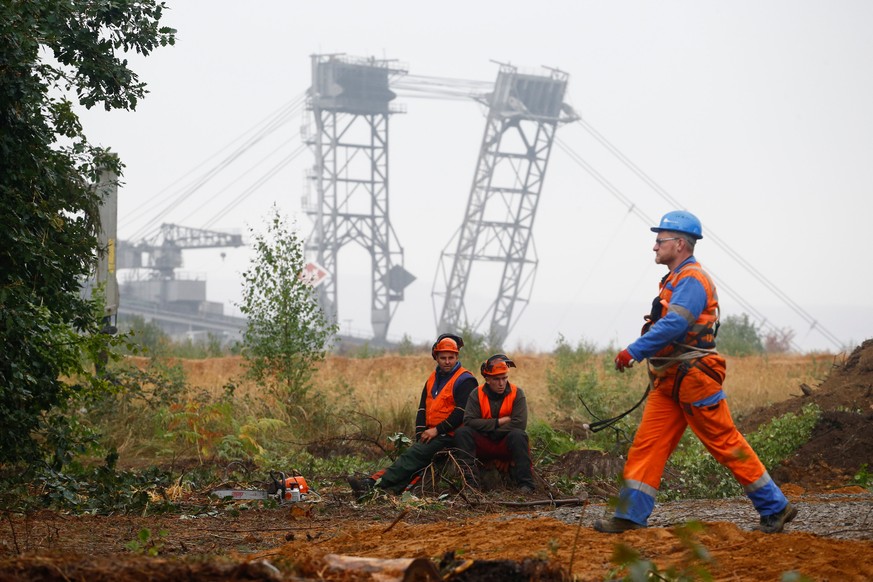 Lumberjacks of German utility and power supplier RWE are seen in front of a brown coal excavator of the Hambach open-cast mining of RWE next to the forest &quot;Hambacher Wald&quot; where activists ar ...
