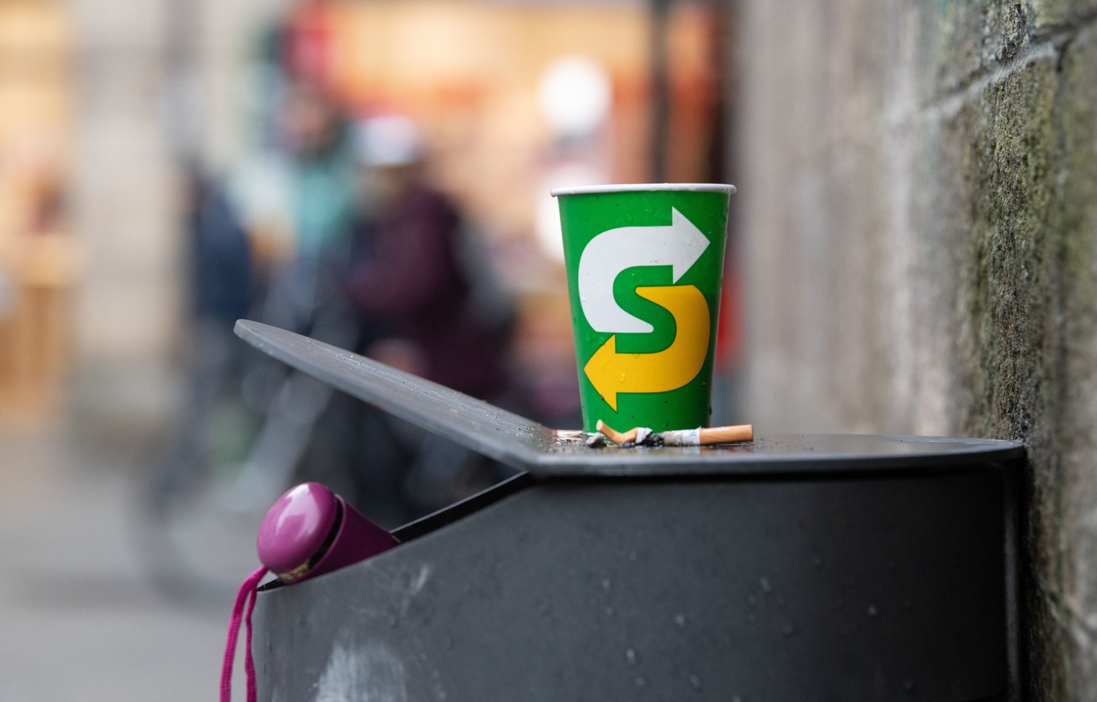 Ein Pappbecher steht auf einem Mülleimer bei der Stiftskirche. Zur Reduzierung des Mülls im öffentlichen Raum will die Stadt Tübingen eine Steuer auf Einwegverpackungen von Speisen und Getränken erheb ...