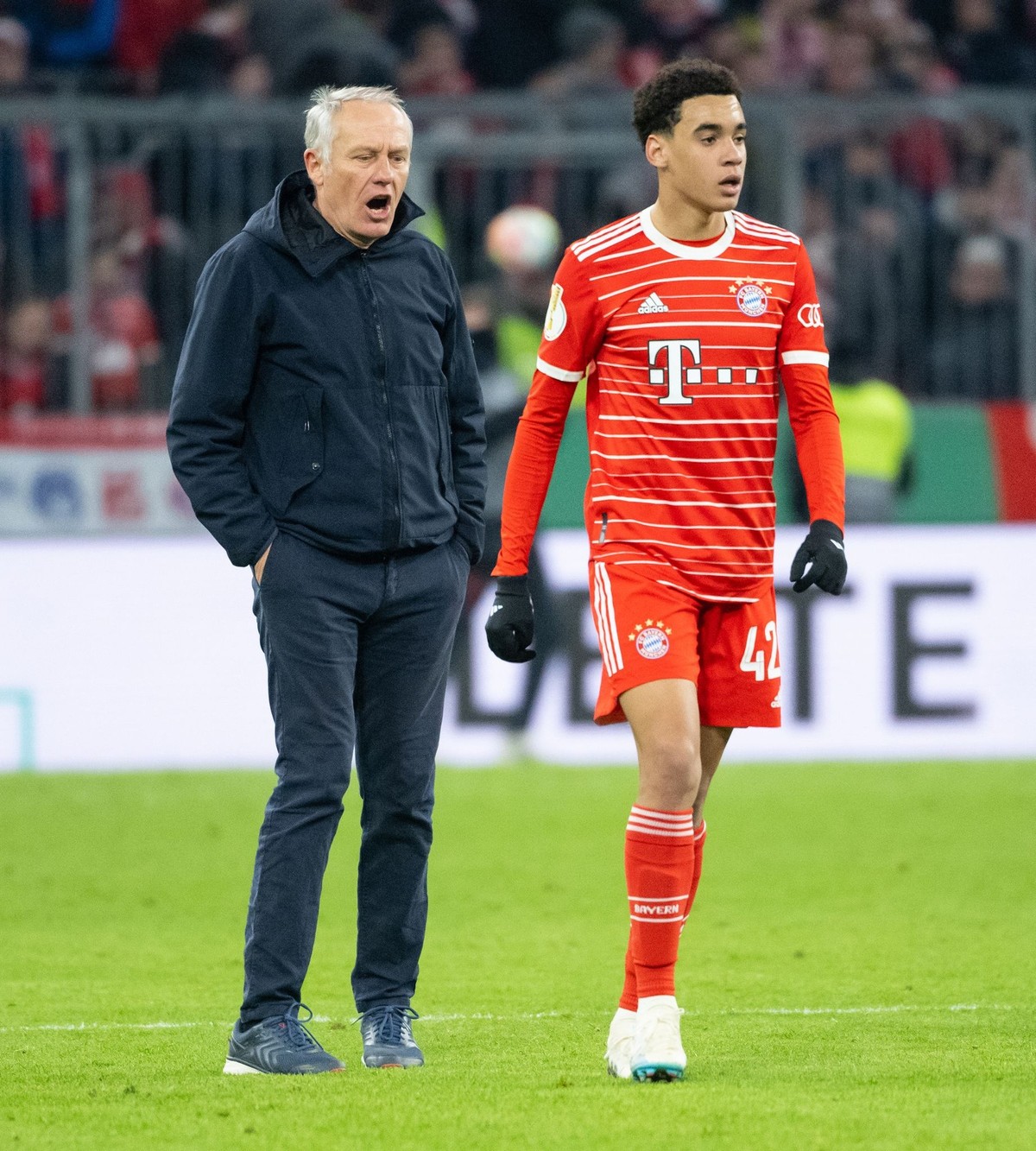 04.04.2023, Bayern, München: Fußball: DFB-Pokal, Bayern München - SC Freiburg, Viertelfinale in der Allianz Arena. Trainer Christian Streich (l) von Freiburg und Jamal Musiala von München stehen nach  ...