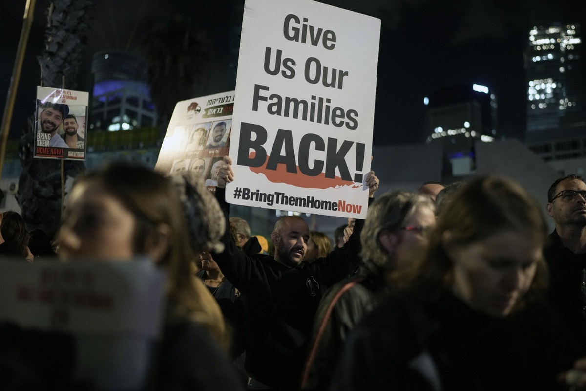 A man holds a sign calling for the release of the hostages taken by Hamas militants into the Gaza Strip during a demonstration at the Hostages Square in Tel Aviv, Israel, Saturday Jan. 13, 2024. Sunda ...