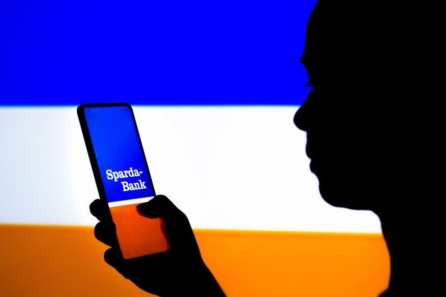 BRAZIL - 2022/03/25: In this photo illustration, a woman&#039;s silhouette holds a smartphone with the Sparda-Bank Hessen logo displayed on the screen. (Photo Illustration by Rafael Henrique/SOPA Imag ...