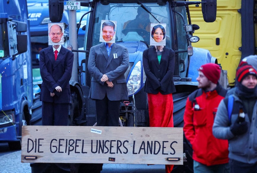 Figures with the pictures of German Chancellor Olaf Scholz, Economy and Climate Minister Robert Habeck and Foreign Minister Annalena Baerbock are seen in front of a tractor with a board that reads &#0 ...