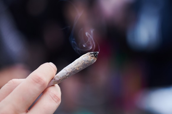 ARCHIV - 12.08.2023, Berlin: Eine Frau h�lt einen Joint in der Hand. Die Koalition hat sich am Donnerstagabend abschlie�end auf die Legalisierung von Cannabis geeinigt. (zu dpa: �Koalition einig: Cann ...