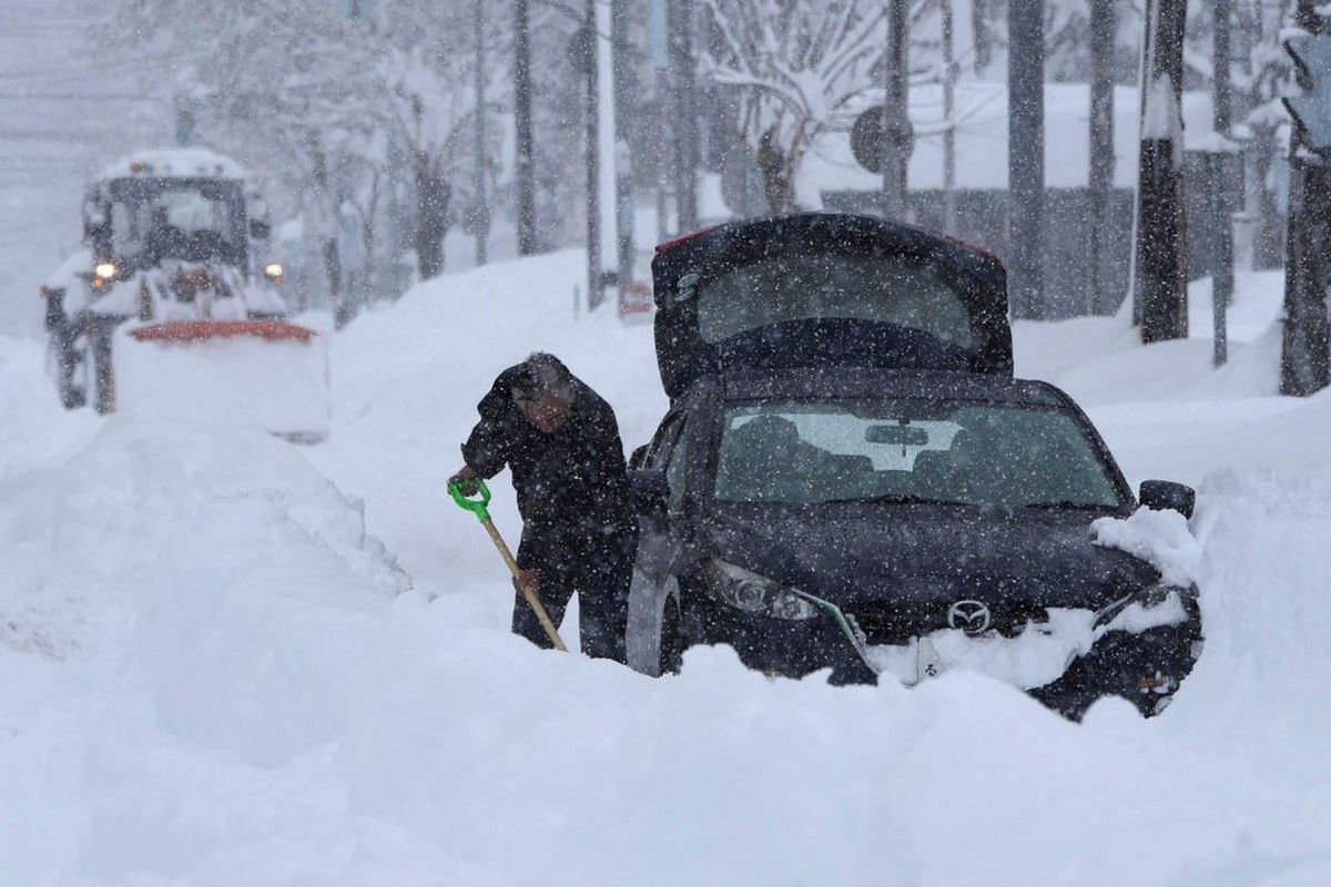 A man tries to dig his car out with a shovel as snow falls across northern Japan, in the city of Obihiro, Hokkaido prefecture on February 4, 2025. (Photo by JIJI Press / AFP) / Japan OUT (Photo by STR ...