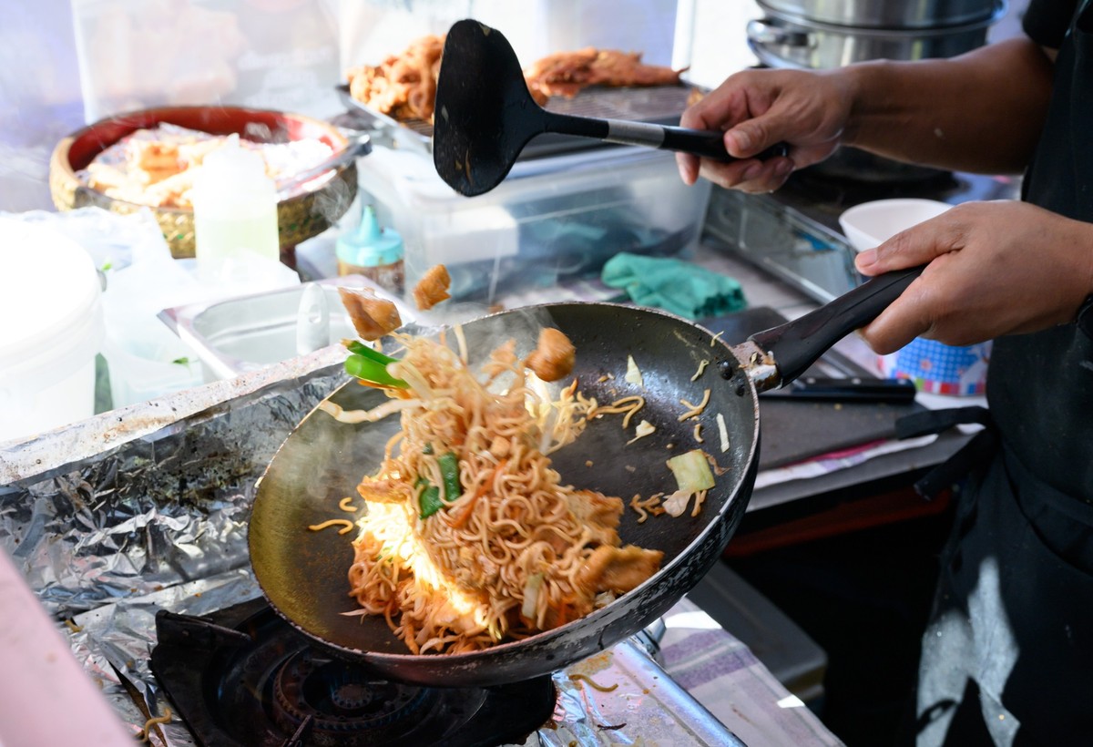 ARCHIV - 15.09.2023, Berlin: Ein Mensch kocht in seiner mobilen Küche auf dem Thai-Streetfood-Markt im Preußenpark in Berlin-Wilmersdorf. Von Frühjahr bis Herbst wird im sogenannten Thaipark an vielen ...