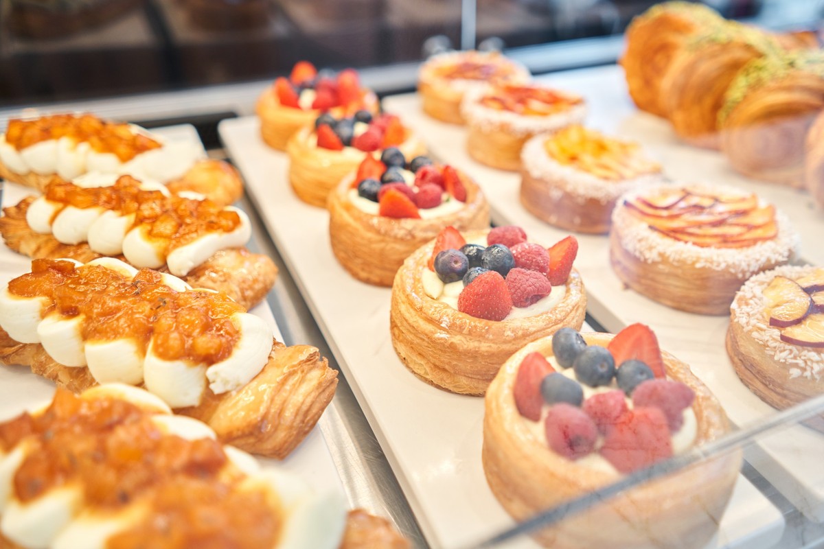 A variety of fresh pastries in the bakery window. almond croissant is fresh and hot in a cafe next to other types of pastries. The interior of an Italian restaurant. High quality photo xkwx assortment ...
