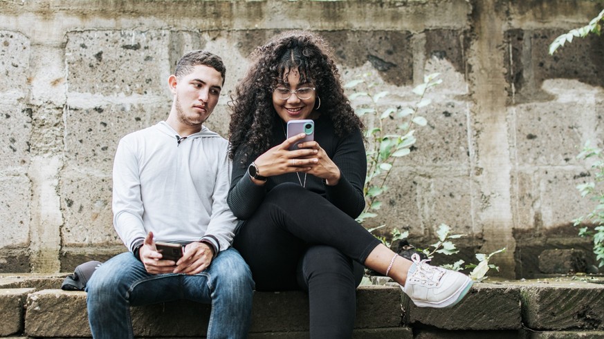 Suspicious person spying on his girlfriend phone, Jealous guy spying on his girlfriend phone, Distrustful boyfriend spying on his girlfriend phone