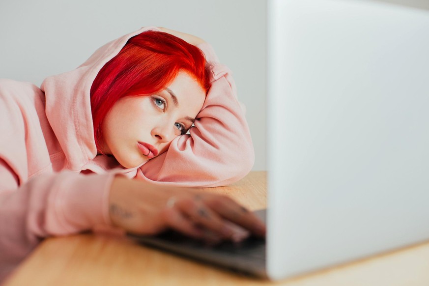 Portrait of a teenager lying on desk using in laptop computer to surf internet