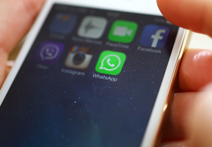 Wien,Austria-February 25,2014: Closeup of female hand holding an iPhone 5s while launching WhatsApp,a popular messaging application .