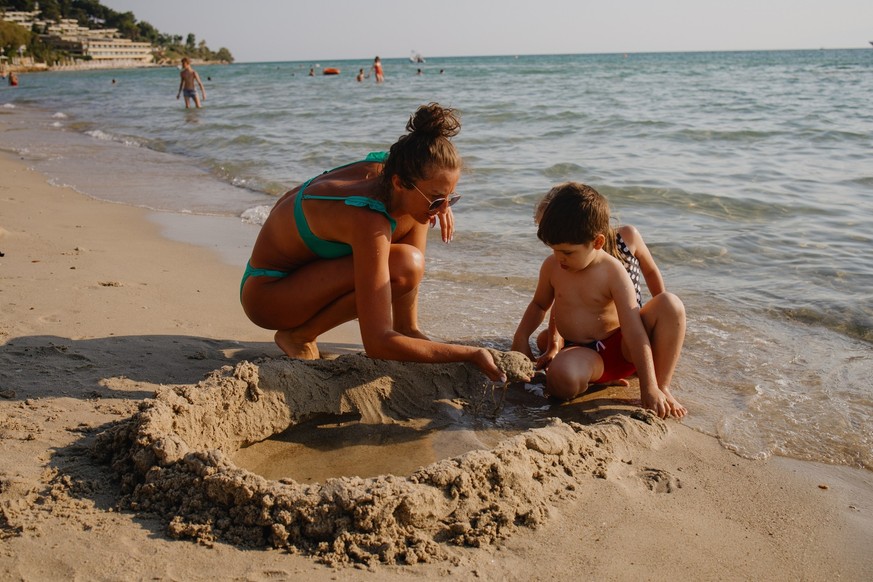 Happy family is building sandcastle on a beach on a sunny summer day