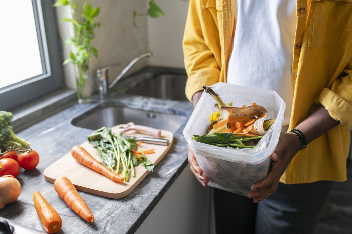 Man holding vegetable waste in container at home model released, Symbolfoto property released, VRAF00582