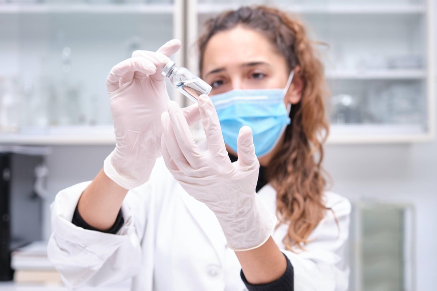 Young female scientist wearing face mask holding a coronavirus vaccine vial. Covid-19 vaccine development. Madrid, Community of Madrid, Spain PUBLICATIONxINxGERxSUIxAUTxONLY CR_CRVI201216-591546-01 ,m ...