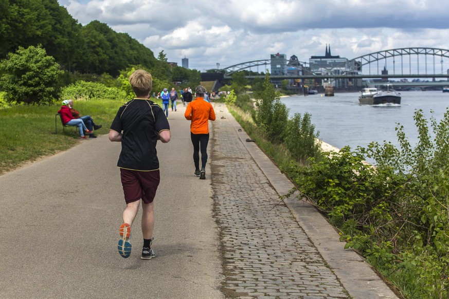 Jogger sind während des Kontaktverbots wegen der Coronapandemie am Rheinufer unterwegs. Jogger am Rhein *** Joggers are out and about on the Rhine during the ban on contact due to the corona pandemic  ...