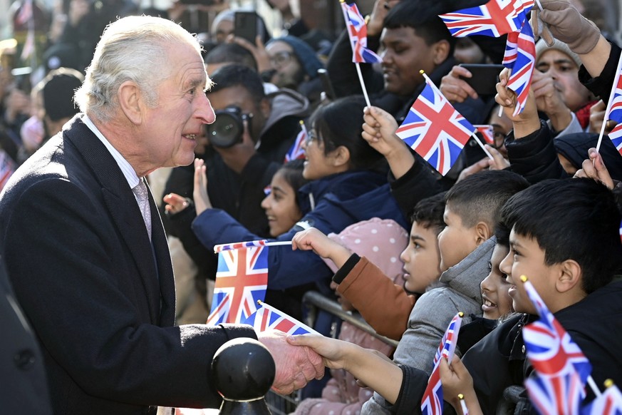 08.02.2023, Großbritannien, London: König Charles III. begrüßt Kinder, während er und die Königsgemahlin die Brick Lane im Osten Londons besuchen, um sich mit Wohltätigkeitsorganisationen und Unterneh ...